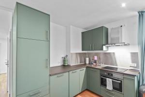 - une cuisine avec des placards verts et une cuisinière four supérieur dans l'établissement Flatista Homes - Central Station - 3BR, à Munich