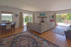 uma sala de estar com um sofá e uma sala de jantar em Frosty's Retreat - Great Barrier Island Home em Tryphena