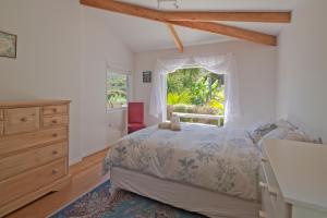 a bedroom with a bed with a dresser and a window at Frosty's Retreat - Great Barrier Island Home in Tryphena