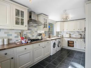 a kitchen with white cabinets and a washer and dryer at Sid Valley View - Scenic end of terrace town house in Sidmouth
