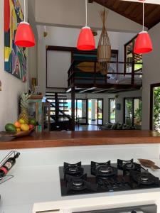 uma cozinha com um fogão e luzes pendentes vermelhas em Casa Buena Vista em Arraial d'Ajuda