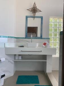 a white bathroom with a sink and a mirror at Casa Buena Vista in Arraial d'Ajuda