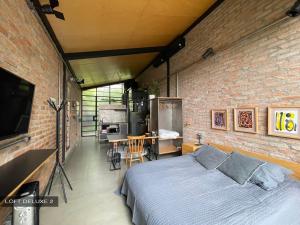 een slaapkamer met een bed en een bakstenen muur bij Degar Studios in Sao Paulo