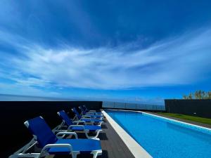 a row of chairs sitting next to a swimming pool at Vivenda Luxuosa in Feteiras