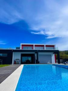una casa con piscina frente a una casa en Vivenda Luxuosa, en Feteiras