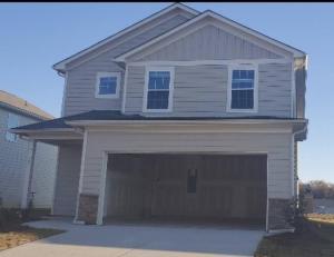 a white house with a large garage at New 3 Bedroom Home w/ tons of amenities & parking. in McDonough