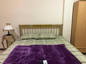 a bed with a purple blanket on top of it at Apartment near Abdeen Palace & Museum in Cairo
