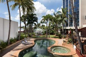 ein Pool mit Palmen und ein Gebäude in der Unterkunft Rydges Southbank Townsville in Townsville