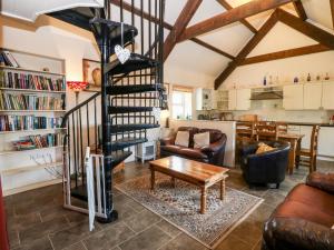a living room with a spiral staircase and a table at Bwthyn y Dderwen Oak Cottage in Llannor