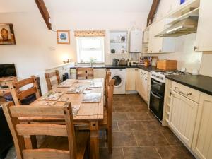 a kitchen with a wooden table and chairs and a stove at Bwthyn y Dderwen Oak Cottage in Llannor