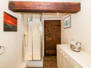 a bathroom with a shower and a sink at Bwthyn y Dderwen Oak Cottage in Llannor +9 photos