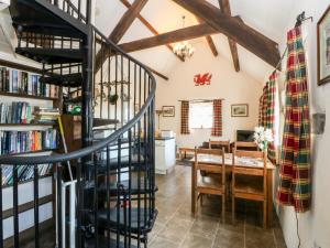 eine Wendeltreppe in einem Wohnzimmer mit einem Esszimmer in der Unterkunft Bwthyn yr Onnen Ash Cottage in Llannor