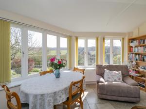a living room with a table and chairs and windows at Clock Tower Cottage in Great Bedwyn