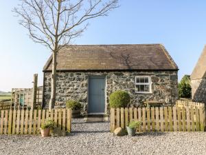 Cabaña de piedra con valla y puerta azul en Bwthyn Celyn Holly Cottage en Llannor