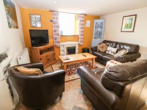 uma sala de estar com mobiliário de couro e uma televisão em Bwthyn Celyn Holly Cottage em Llannor