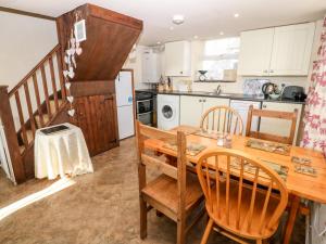 uma cozinha com uma mesa de madeira e cadeiras em Bwthyn Celyn Holly Cottage em Llannor