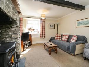 a living room with a couch and a fireplace at Duddon Cottage in Broughton in Furness