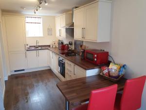 una cucina con armadi bianchi e un tavolo in legno con sedie rosse di Slater's a Portknockie