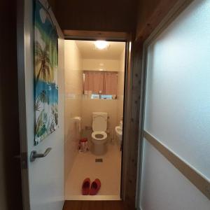 łazienka z toaletą i czerwonymi butami w drzwiach w obiekcie 民泊まったりん人 w mieście Janadō