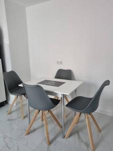 a table with three black chairs and a white table at KM2 Apartment in Triberg