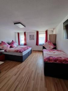 two beds in a room with wooden floors and red curtains at KM2 Apartment in Triberg