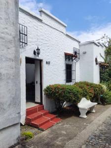 a white building with a door and a red staircase at Cabaña 52 en la Aldea Doradal Santorini Colombiano in Doradal