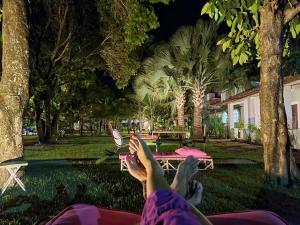 uma pessoa deitada numa rede de descanso num parque à noite em Villa Ostello Pousada em Paripueira