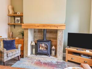 a living room with a fireplace and a tv at Maria Cottage in Haworth