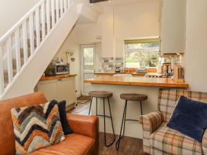 eine Küche und ein Wohnzimmer mit einer Theke und Stühlen in der Unterkunft Maria Cottage in Haworth