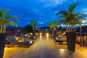 a rooftop deck with lounge chairs and palm trees at night at Hotel Republicano 1910 in Girardot