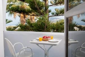 uma mesa com uma tigela de frutas e bebidas numa varanda em Daedalus Hotel em Fira