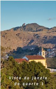 a church on a hill with a mountain in the background at Casinha da Lela in Ouro Preto