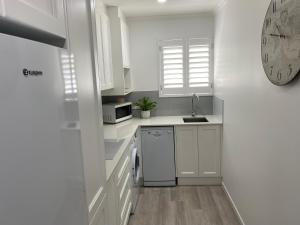 a white kitchen with a sink and a dishwasher at Rainbow Beach Dream in Rainbow Beach