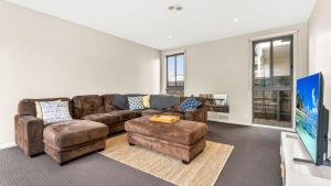 a living room with a brown couch and ottoman at Bliss on Sanctuary in Cowes