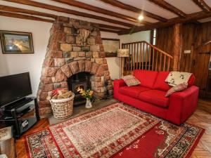 a living room with a red couch and a stone fireplace at Elm Cottage in Warcop