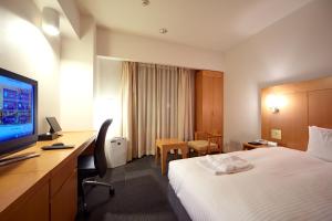 a hotel room with a bed and a desk and a television at Hotel Rocore Naha in Naha