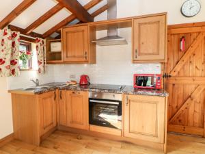 a kitchen with wooden cabinets and a stove top oven at Heath Cottage in Edale
