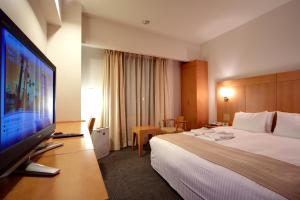 a hotel room with a bed and a flat screen tv at Hotel Rocore Naha in Naha