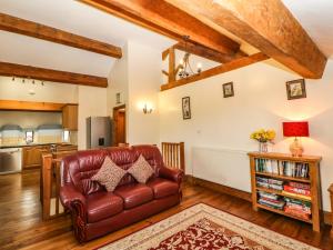 a living room with a leather couch and a kitchen at Meadow View in Edale