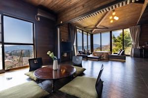 VILLA HAKONE湖空 في هاكوني: غرفة معيشة مع طاولة وكراسي ونوافذ