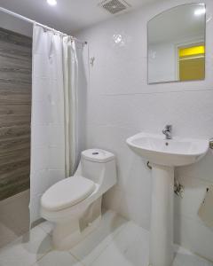 a white bathroom with a toilet and a sink at Malecon Rooms y Hotel in Santo Domingo