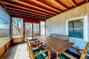 - une table et des chaises en bois sur la terrasse couverte d'une maison dans l'établissement Cold Storage Beach Cottage, à Truro