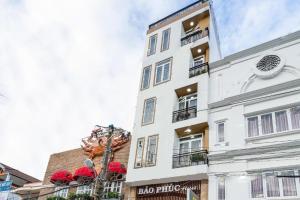 a tall white building with red umbrellas on it at Bao Phuc Hotel in Phu Quoc +18 photos