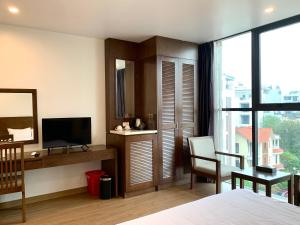 a bedroom with a bed and a desk and a television at HOTEL Blue Rose in Hai Phong