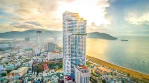 een hoog gebouw naast een strand en de oceaan bij GRAND HYCHARMS Serviced 2BR APARTMENT View Cầu Nhơn Hội in Quy Nhon