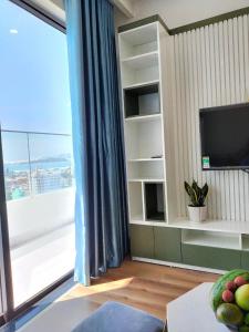 een woonkamer met een tv en een groot raam bij GRAND HYCHARMS Serviced 2BR APARTMENT View Cầu Nhơn Hội in Quy Nhon