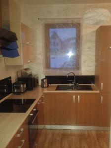 a kitchen with wooden cabinets and a sink and a window at Apartament Ostoja in Szczawnica