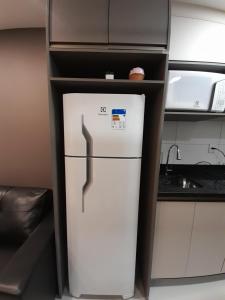 a white refrigerator in a kitchen next to a shelf at Apartamento bem localizado in Bento Gonçalves