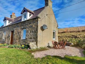 a stone house with two chairs in front of it at Ornum in Skerray