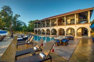 a resort with a swimming pool and chairs and a building at Mariposa Belize Beach Resort in Placencia